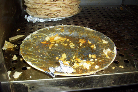 Poppadoms stored on a plate covered in greasy, damaged foil